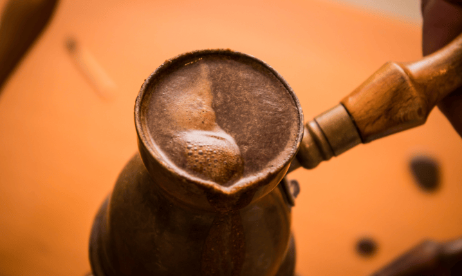 café turco: uma cafeteira de metal como um copo com cabo de madeira, onde se aquece a água com o café moído e depois serve direto, esperando decantar o sólido
