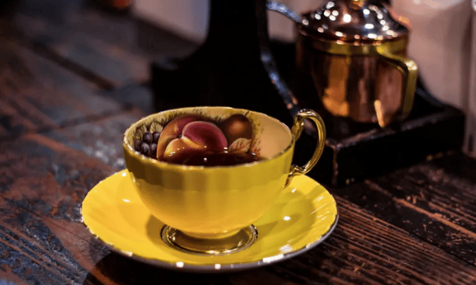 xícara de porcelana típica japonesa com detalhes em ouro e desenhos de frutas na parte interior