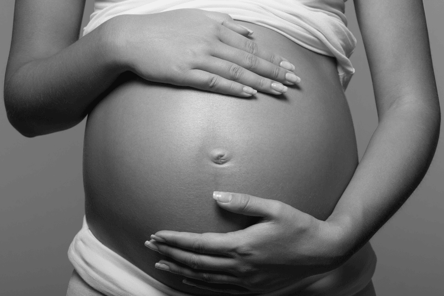 mulher gestante com as mãos sobre a barriga