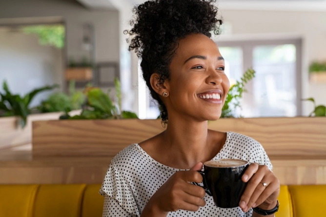 mulher negra sorridente tomando café