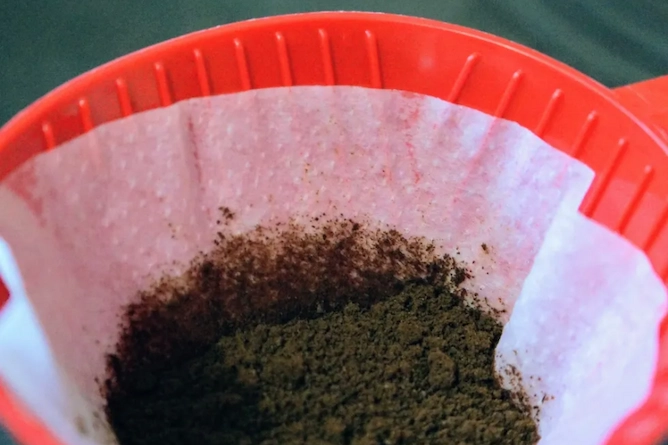 coador de café chamado de melitta, de plástico com ranhuras na vertical e dentro um filtro de papel com café moído