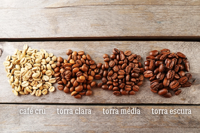 da esquerda para a direita, temos quatro tipos de grãos de café: cru, torrado claro, torrado médio e torrado escuro