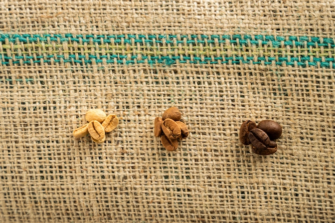 da esquerda para a direita temos três montinhos de grãos de café: cru, torrado claro e torrado escuro
