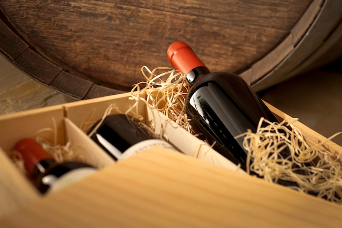 caixa de madeira com três vinhos dentro e alguns fios de palha para decoração da caixa