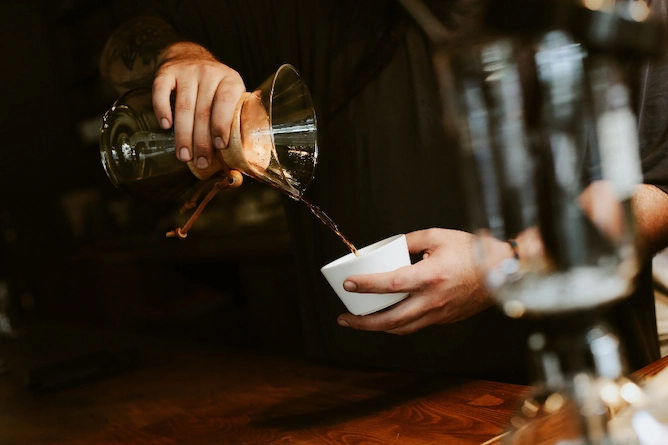 pessoa servindo o café da chemex, na foto, dá pra ver que é um café menos denso