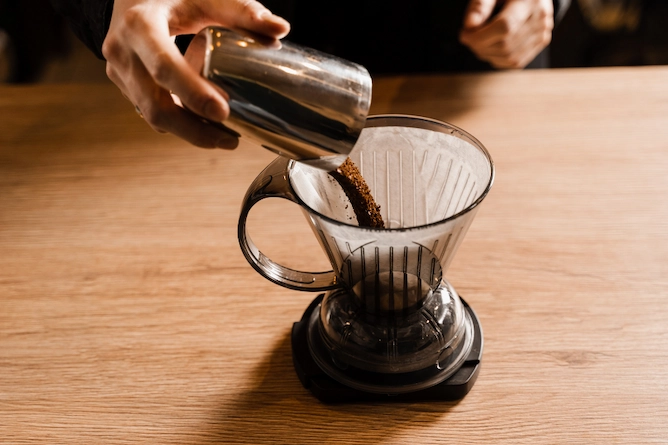 método clever sob uma mesa de madeira, já com o filtro de papel, sendo colocado o café moído